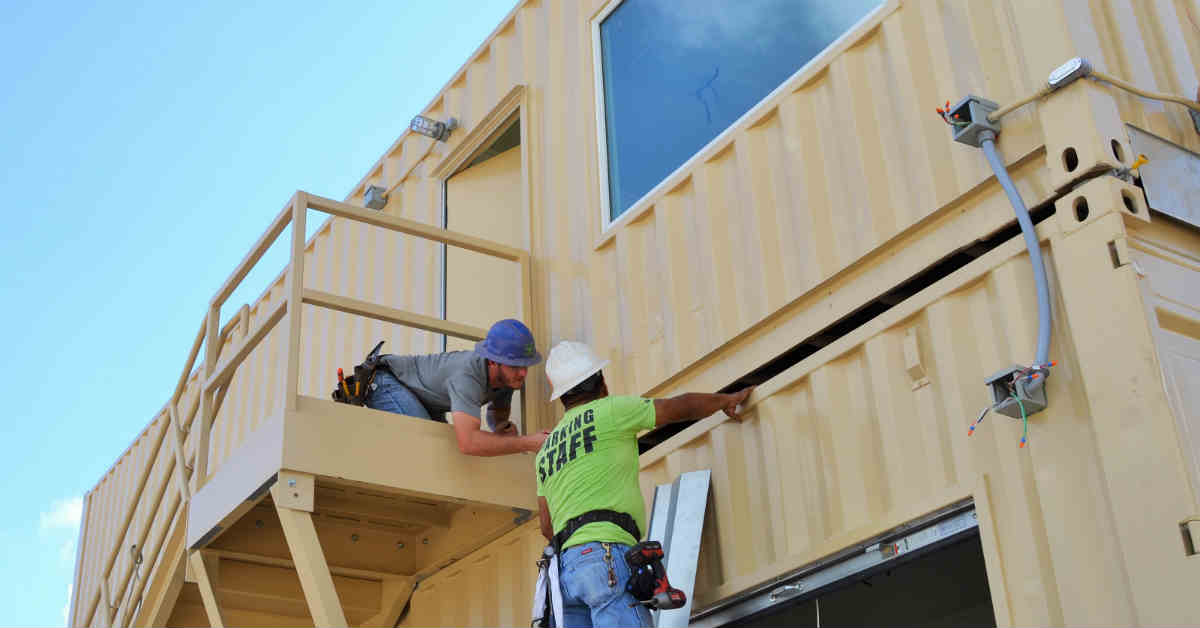 Two Falcon employees perform a quality control check on a custom shipping container building. Two Falcon employees perform a quality control check on a custom shipping container building.
