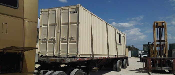 Shipping container module loaded on truck for modular construction.
