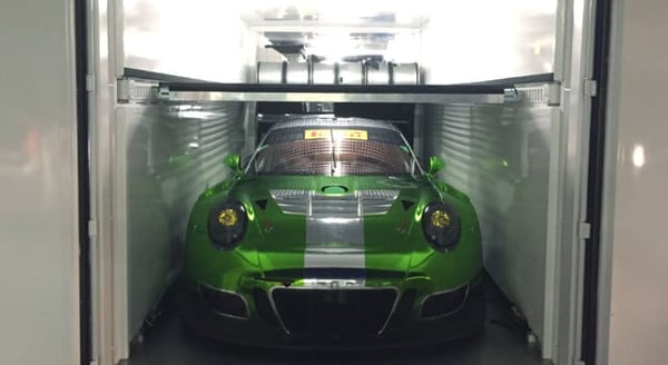 Porsche 911 inside mobile car garage made from conex container