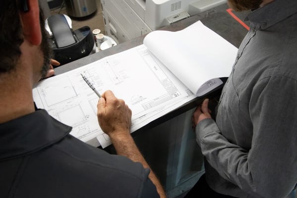 engineers review blueprints of shipping container modifications