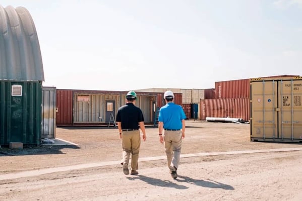 an architect and engineer walk between shipping container structures