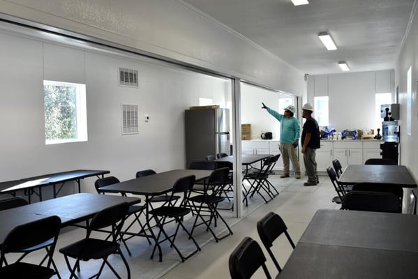construction workers standing inside a modified shipping container breakroom