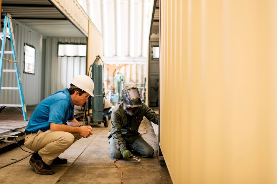 two men looking at a modified shipping container in production