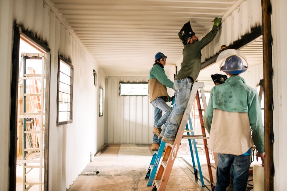 men measuring and marking the inside of a shipping container