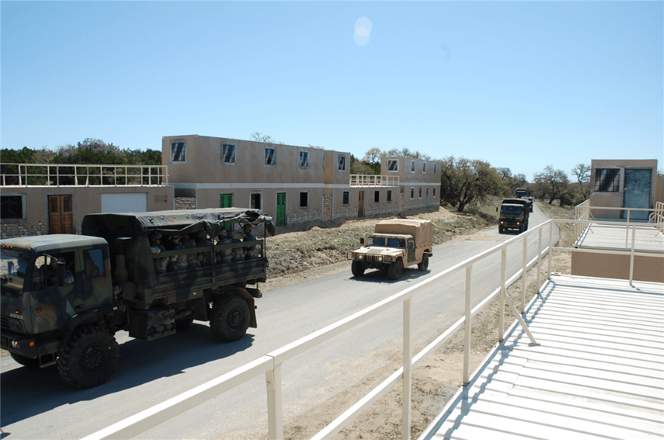 shipping container military training village MOUT with military vehicles driving on the road