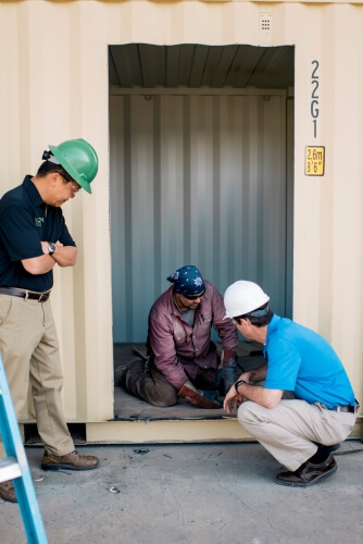 three men inspecting shipping container modifications
