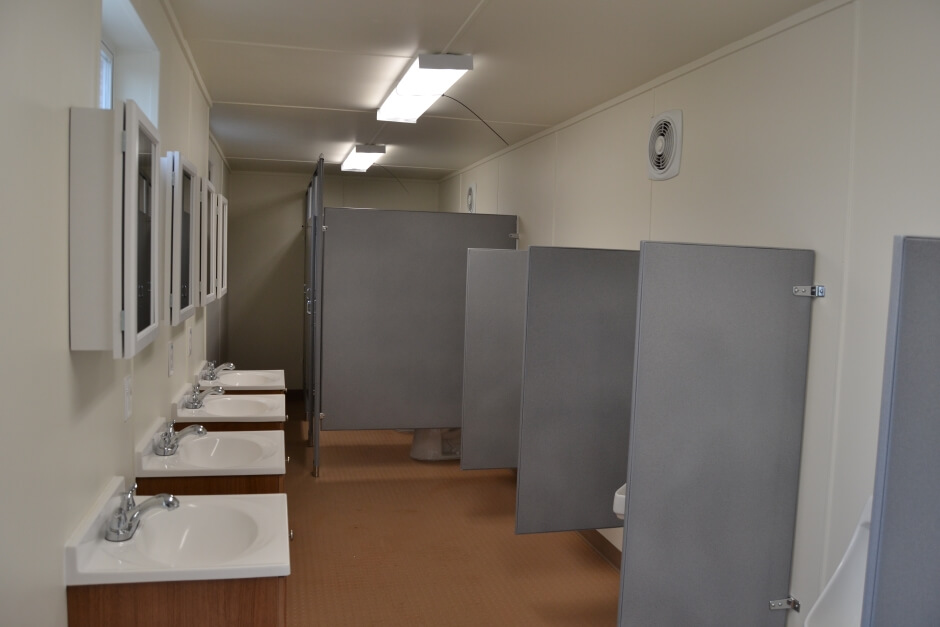 shipping container bathroom interior with four sinks and bathroom stalls