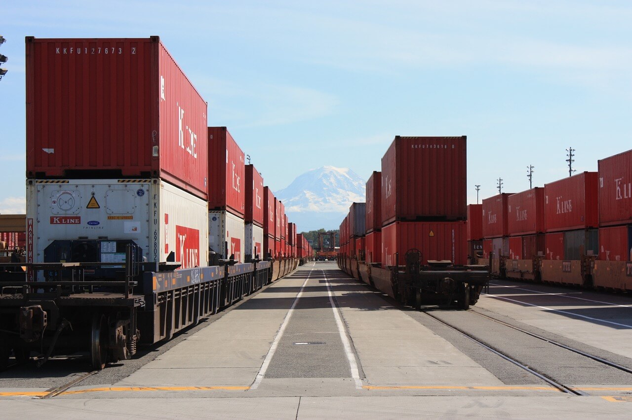shipping containers on multiple trains with mountain in the back