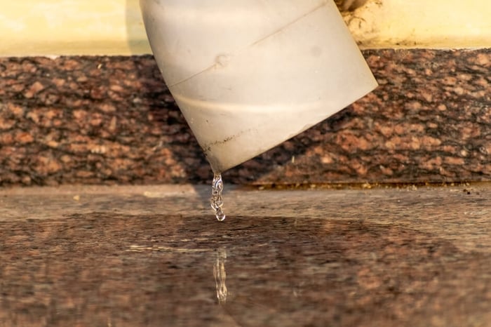 PVC plumbing pipe dripping water into a puddle