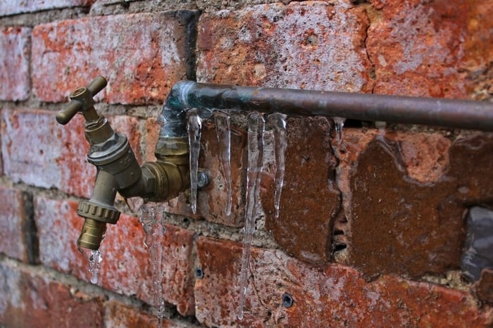 frozen water spout on brick wall