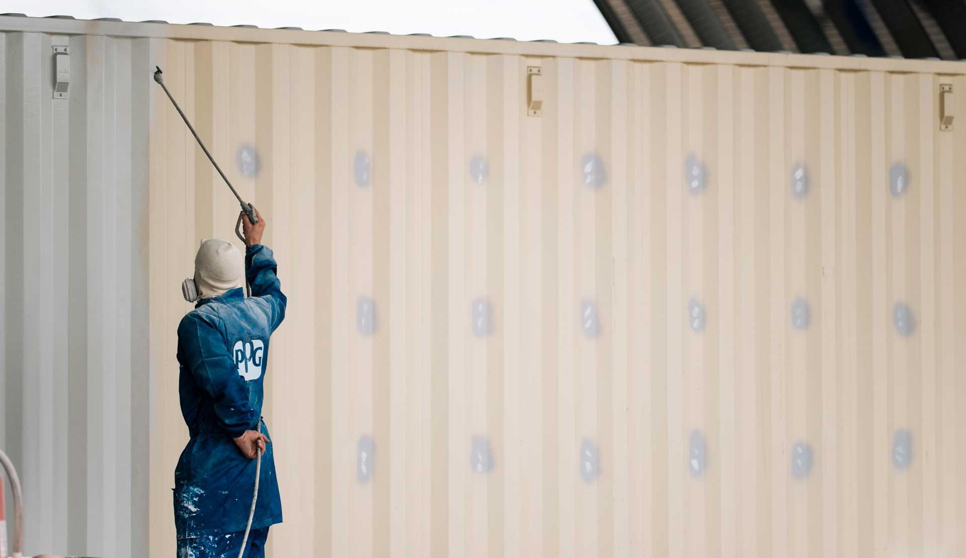 man painting exterior of shipping container