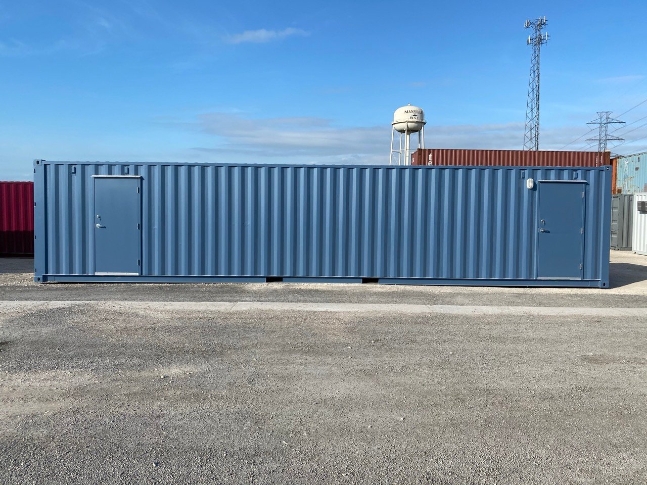 Blue_shipping_container_with_two_doors_on_gravel_lot_under_clear_sky