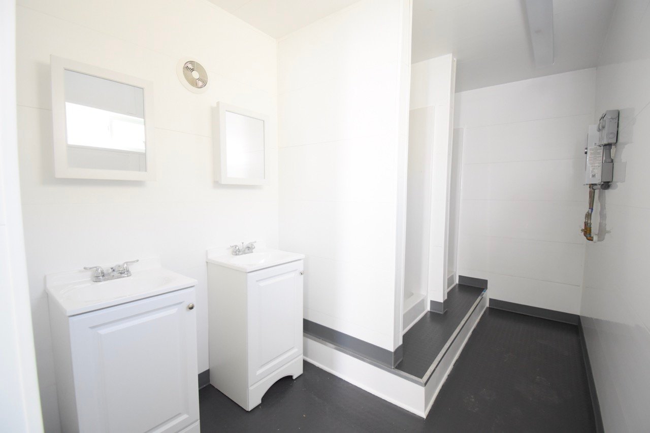 locker room bathroom with showers and sinks