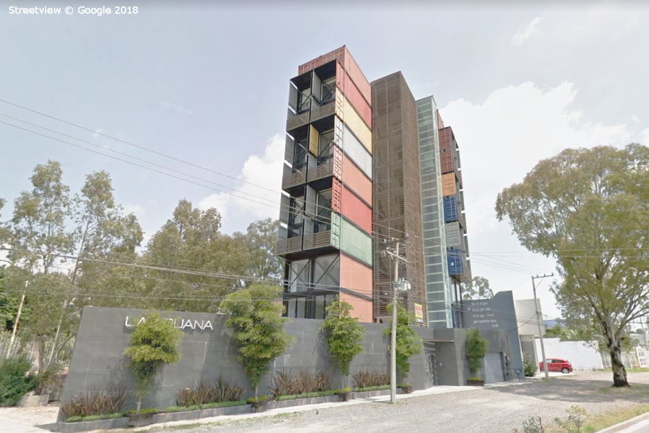 man spray painting a shipping container grey 