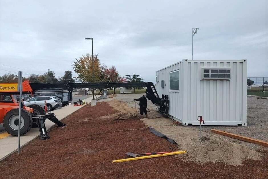 man spray painting a shipping container grey 