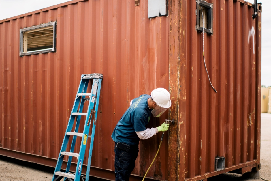 workers adding frames to the inside of a modified shipping container