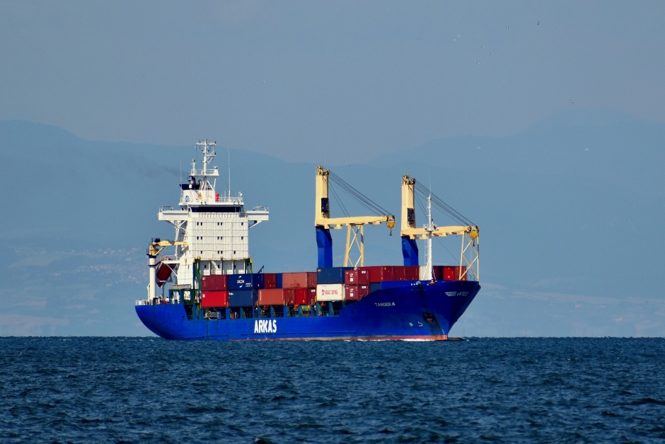 green shipping containers on a blue tilt bed truck, train, and boat