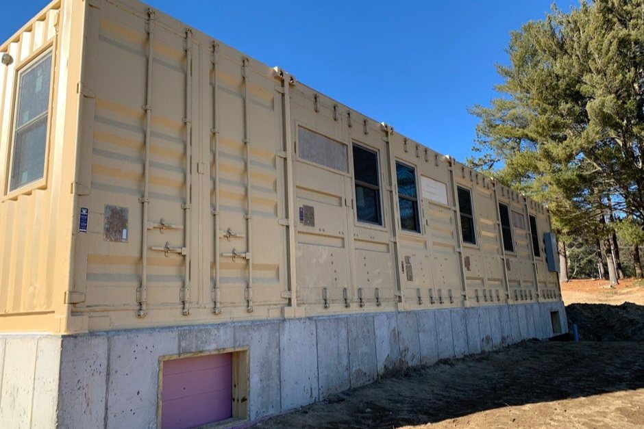 modified shipping container office with green stripe and rent vs. buy text